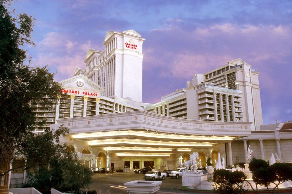 The exterior of Caesars Palace hotel and casino in Las Vegas, featuring its grand entrance, illuminated signage, and classical architectural elements at dusk.