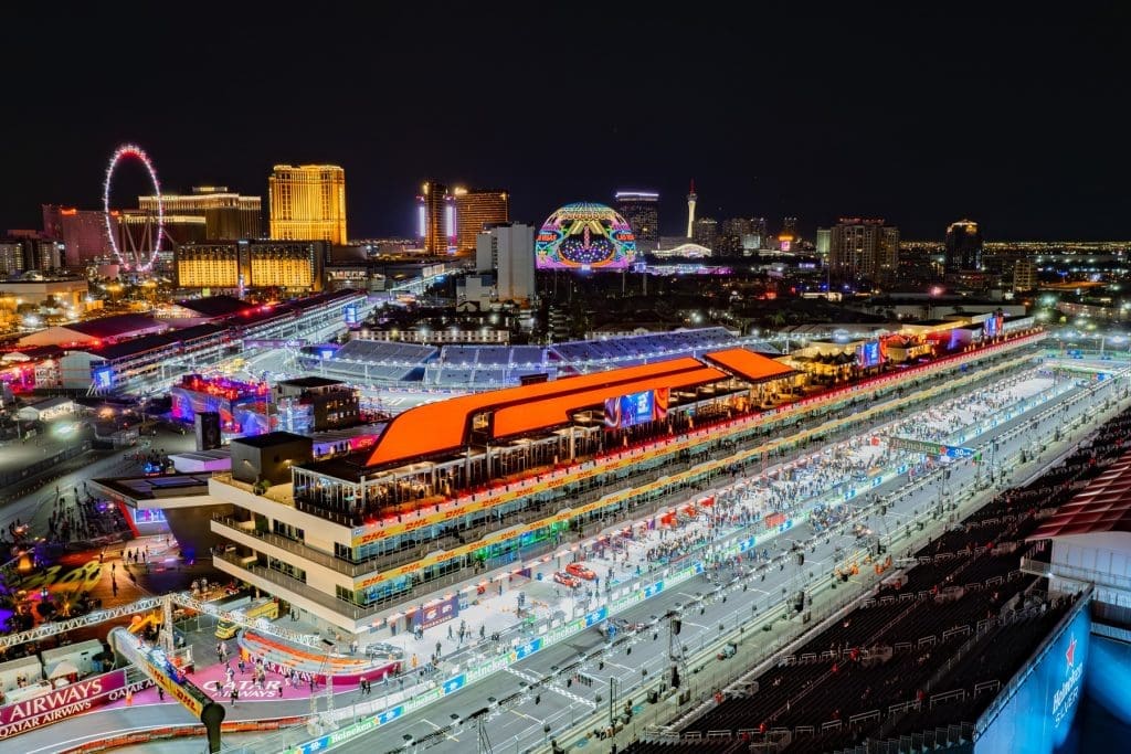 A brightly lit Formula 1 racetrack in Las Vegas at night, with grandstands, crowds, and city lights visible in the background.