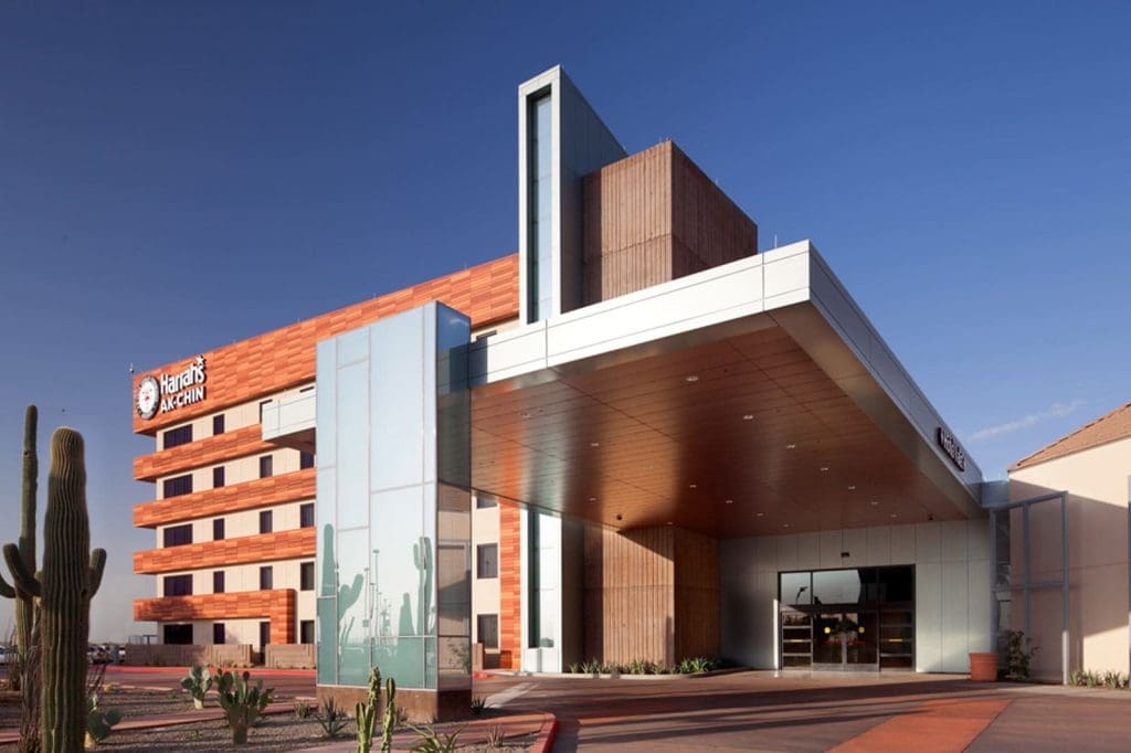 Modern multi-story building with a large covered entrance, desert landscaping, and signage that reads "Harrah’s Ak-Chin" on the exterior.
