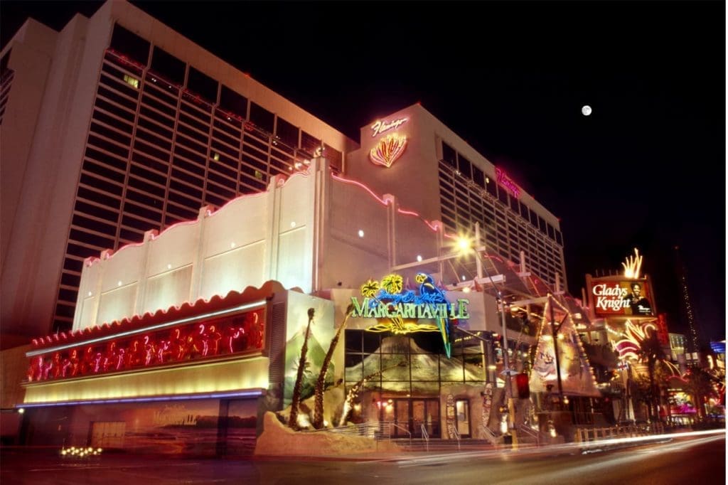 Night view of the Flamingo Las Vegas hotel and casino with neon lights, featuring Margaritaville and Gladys Knight signs.