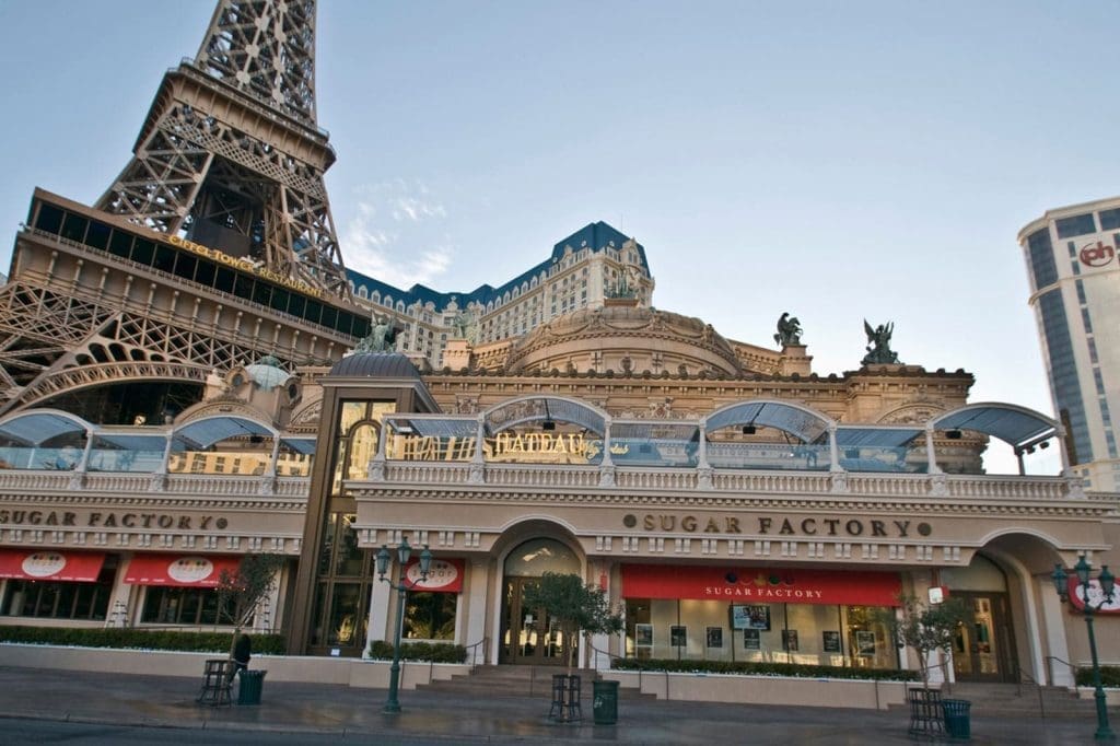 The exterior of the Sugar Factory restaurant at the Paris Las Vegas Hotel, with the Eiffel Tower replica and ornate architecture visible in the background.