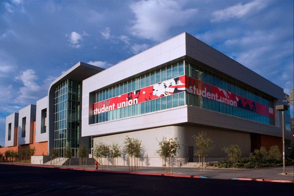 A modern building labeled "student union" with large windows, a red and white banner, and a small landscaped area in front.