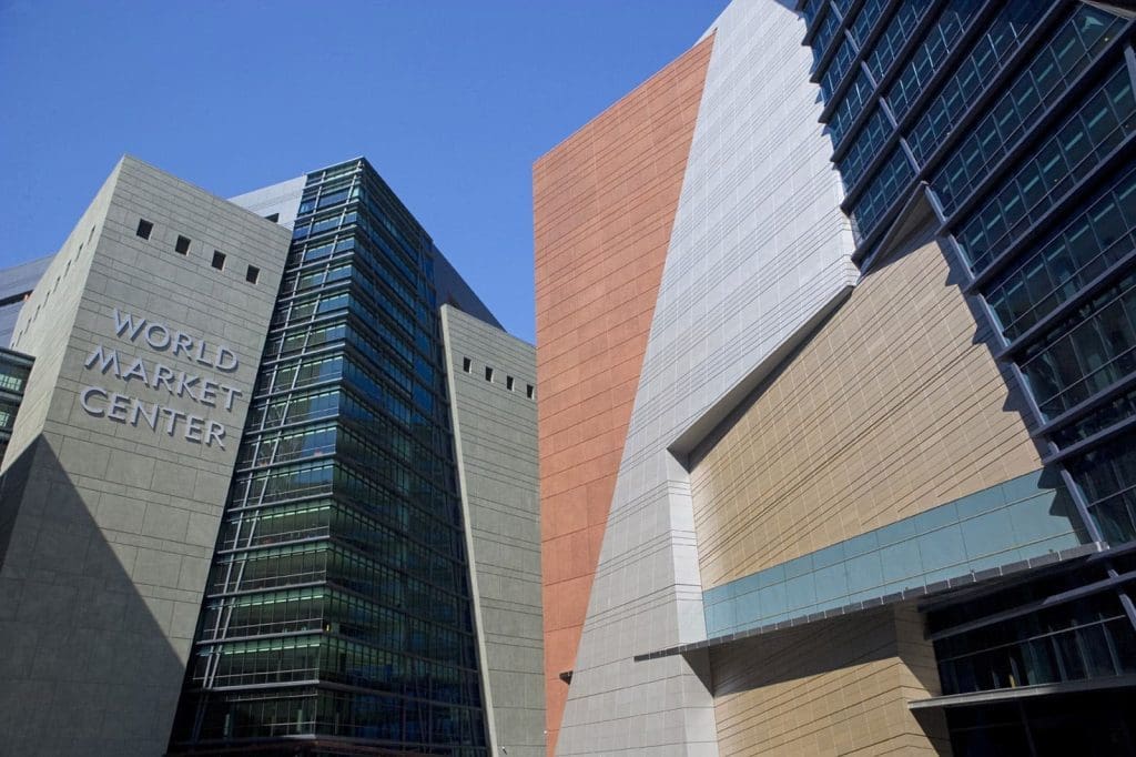 Glass and concrete buildings of the World Market Center with sharp angles and geometric patterns under a clear blue sky.
