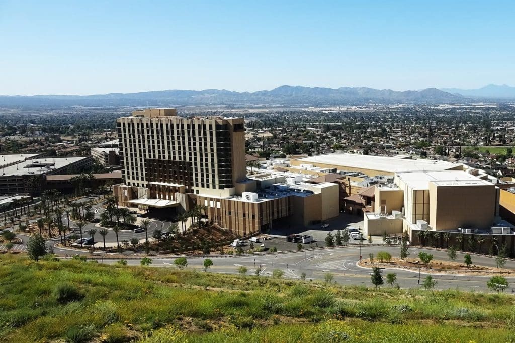 A large hotel and casino complex is surrounded by roads and parking areas, set against an urban landscape and distant mountains under a clear sky.