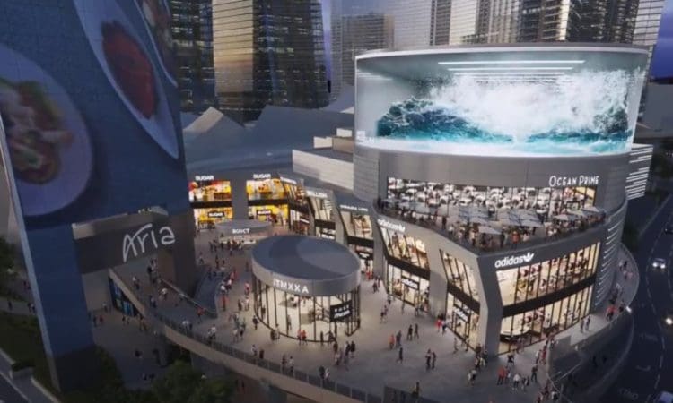 A busy urban plaza with crowds, modern buildings, large digital screens, and storefronts including Adidas, Ocean Prime, and others, set against tall glass skyscrapers.