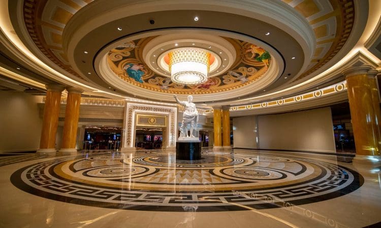 Spacious, ornate hotel lobby with a large circular ceiling, central statue, decorative columns, patterned floor, and a prominent chandelier.