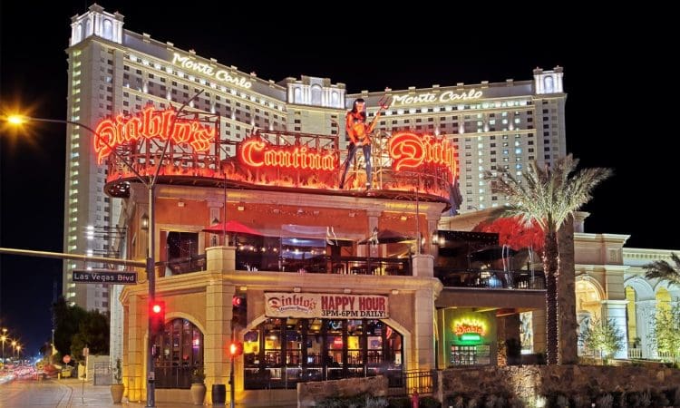 Diablo's Cantina bar and restaurant with neon signs lit up at night, with the Monte Carlo hotel in the background on Las Vegas Boulevard.