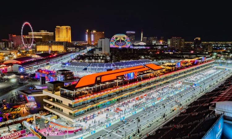 A brightly lit Formula 1 racetrack in Las Vegas at night, with grandstands, crowds, and city lights visible in the background.