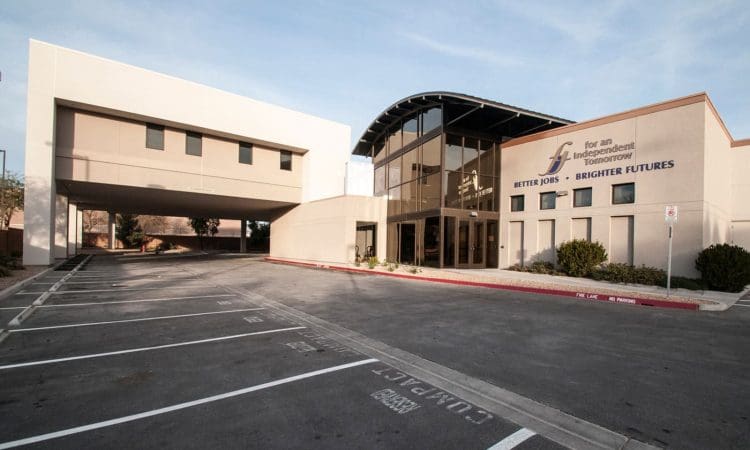 Modern office building with large glass entrance and a drive-through section; logo and slogan "Better Jobs. Brighter Futures." visible on the facade; empty parking lot in front.
