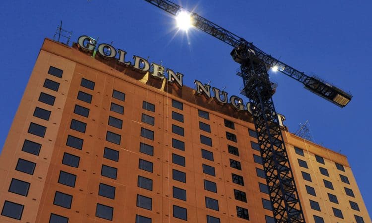 A construction crane is positioned next to the Golden Nugget hotel building at dusk, with its name displayed in large letters on the upper facade.