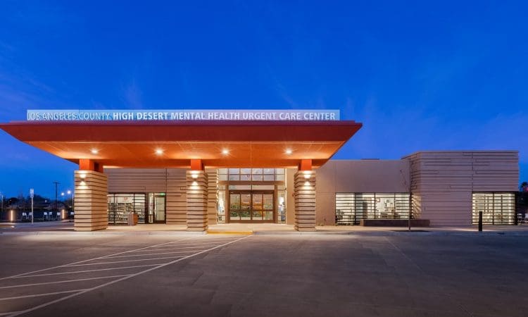 Exterior view of the Los Angeles County High Desert Mental Health Urgent Care Center at dusk, with illuminated signage and modern architecture.
