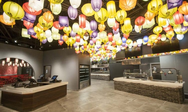 Spacious restaurant interior with colorful paper lanterns hanging from the ceiling, modern counters, and an open kitchen.