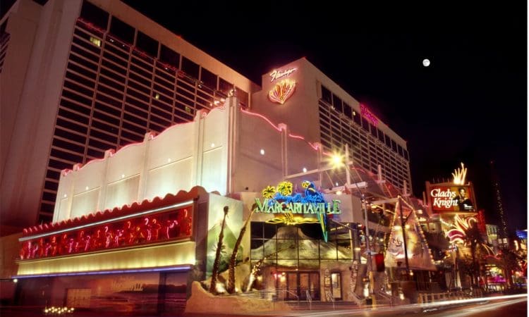 Night view of the Flamingo Las Vegas hotel and casino with neon lights, featuring Margaritaville and Gladys Knight signs.
