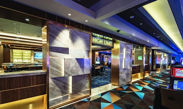 Casino interior with modern decor, patterned carpet, and a sign reading "High Limit"; slot machines and gaming tables are visible in the background.