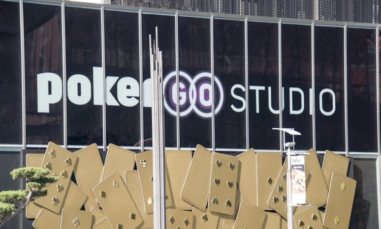 The exterior of a building with large windows displays the "PokerGO Studio" logo above a decorative wall featuring oversized gold playing cards.
