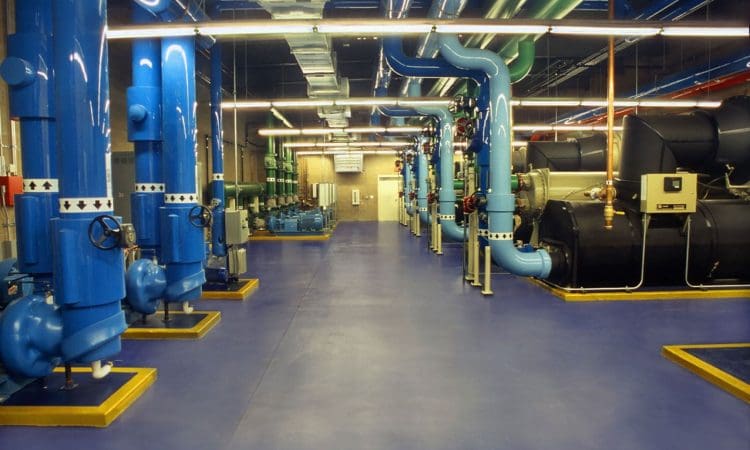 A brightly lit industrial facility with blue and green pipes, large machinery, and polished floors, arranged in organized rows.