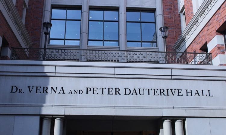 Entrance of Dr. Verna and Peter Dauterive Hall, with the building name prominently displayed above columns and windows in the background.