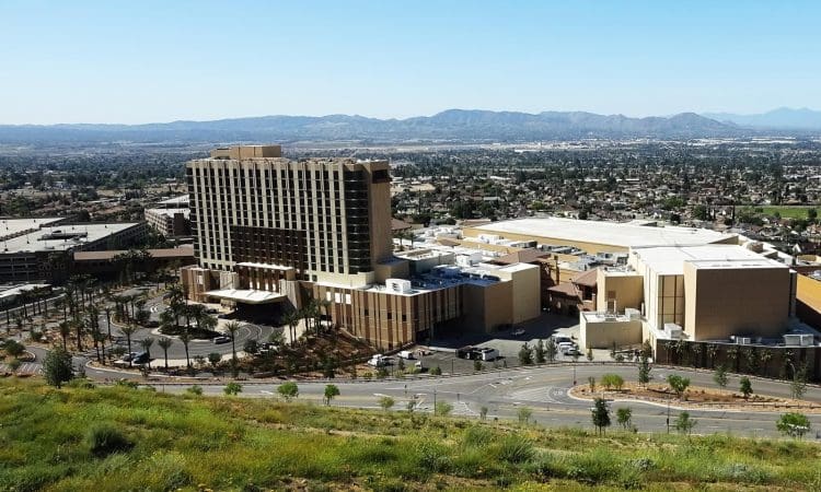 A large hotel and casino complex is surrounded by roads and parking areas, set against an urban landscape and distant mountains under a clear sky.